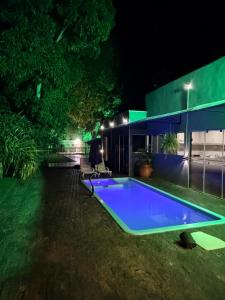 a swimming pool in front of a house at night at Hotel KK 1021 in Coxim