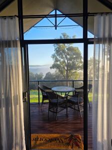 a patio with a table and chairs on a deck at Scarlet Woods Chalets in Quinninup +26 photos