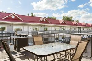 un patio avec une table, des chaises et un grill dans l'établissement Thriftlodge Saskatoon, à Saskatoon