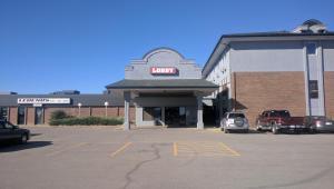 a parking lot in front of a building with a car dealership at Wheatland Hotel in Strathmore