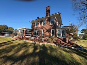 a brick house with a chimney on top of a yard at Historic Ziegler Inn and Suites with Whimsical Themed Rooms in New Bern