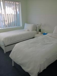 two beds with white sheets in a room with a window at Lakeside view in Cuthbert