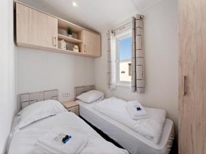 two beds in a small room with a window at Comfortable mobile home in Middelkerke in Middelkerke