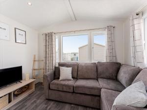 a living room with a couch and a tv at Comfortable mobile home in Middelkerke in Middelkerke