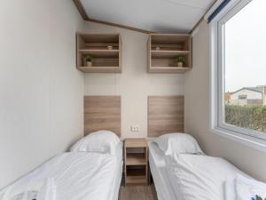 two beds in a small room with a window at Chalet in De Haan with terrace in De Haan