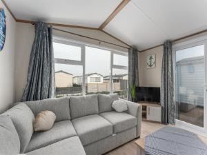 a living room with a couch and a large window at Chalet in De Haan with terrace in De Haan