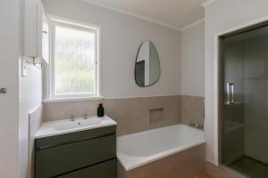 a bathroom with a sink and a tub and a mirror at The Hilltop Hideaway in Tauranga +19 photos