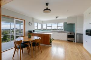 a kitchen with a table and chairs and a kitchen with windows at The Hilltop Hideaway in Tauranga