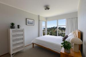 a bedroom with a white bed and a large window at The Hilltop Hideaway in Tauranga