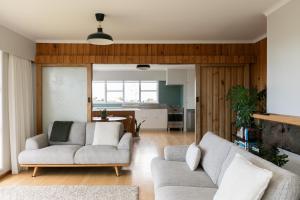 a living room with two couches and a kitchen at The Hilltop Hideaway in Tauranga