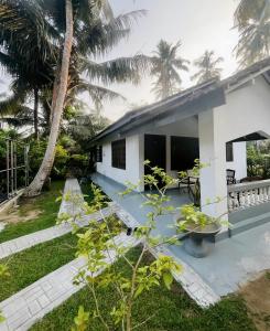 a white house with palm trees in front of it at Windy Oasis in Hikkaduwa