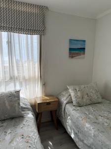 a bedroom with two beds next to a window at Departamento frente a la playa in Arica