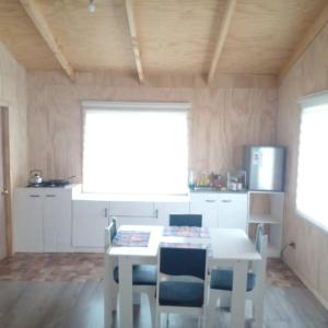 a kitchen with a table and chairs and a window at Cabañas Uenke in Puerto Puyuhuapi