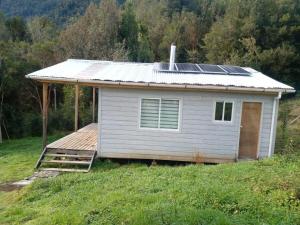 a small house with a roof with a deck at Cabañas Uenke in Puerto Puyuhuapi