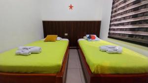 two beds in a room with green sheets at Genovesa Family home in Puerto Ayora