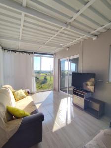 a living room with a couch and a flat screen tv at Beach house - Praia Recreio Torres in Torres