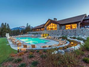 a swimming pool with chairs and a building at Fairmont Jasper Park Lodge in Jasper