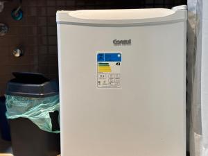 a small white refrigerator next to a trash can at Flat com Ar, Piscina, Garagem, Cozinha e Wi-Fi in Campo Grande