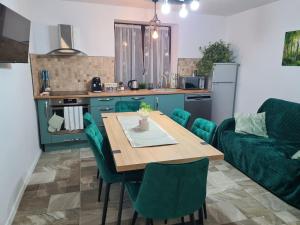 a kitchen with a wooden table and green chairs at Vila Sebas in Zărneşti