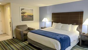 a hotel room with a large bed and a chair at Beacon Inn & Suites in Lincoln