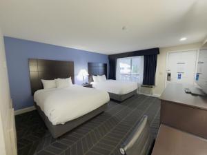 a hotel room with two beds and a desk at Beacon Inn & Suites in Lincoln