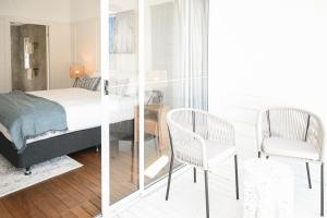 a bedroom with a bed and two chairs at Soluna House in Byron Bay