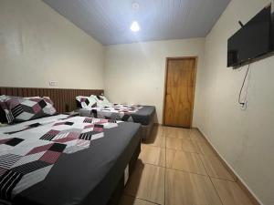 a room with two beds and a flat screen tv at Pousada Taylor in Foz do Iguaçu