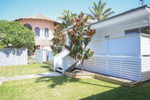 a white house with a tree in a yard at Soluna House in Byron Bay