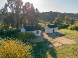 two small white buildings in a field with trees at Cabaña El Quillay in Santa Cruz