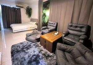 a living room with a couch and chairs and a bed at Ek民宿 in Beihai
