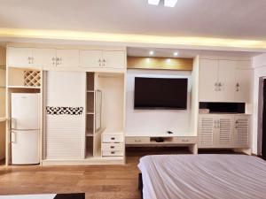 a bedroom with white cabinets and a tv and a bed at Ek民宿 in Beihai