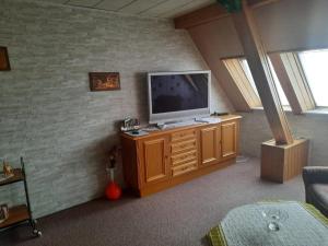 a living room with a television on a wooden cabinet at Ferienwohnung Brockenblick in Halberstadt