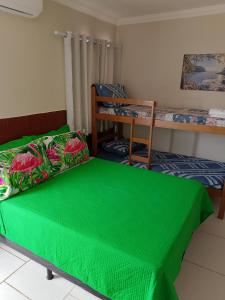 a room with two beds and a green bedspread at Suítes Concha do Sol in Maragogi