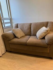 a brown couch in a living room with two pillows at Studio no Sudoeste, vista da 1ª Avenida, tudo a pé in Brasília