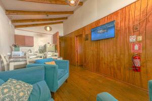a waiting room with blue chairs and a tv on a wall at Algarrobo Cabaña a 2 cuadras Playa El Canelo+Wifi in Algarrobo