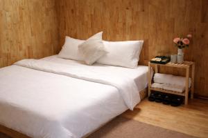 a bed with white sheets and pillows and a table with flowers at Kingfisher Nest in Hai Phong