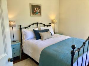 a bedroom with a bed with blue and white pillows at Country Bliss Cottage in Greytown