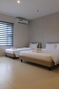 two twin beds in a room with a window at The Perch Hostel in Olongapo +19 photos