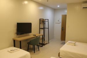 a room with a desk and a tv and a room with two beds at The Perch Hostel in Olongapo