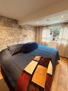 a bedroom with a large bed with a stone wall at La Escondida Cabañas in Mineral del Monte
