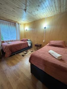 a bedroom with two beds and a wooden ceiling at Cabaña A & M in Chaitén