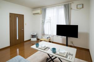 a white living room with a tv and a table at Furano Ski Frante 2 in Furano
