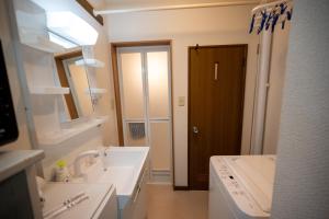 a white bathroom with a sink and a mirror at Furano Ski Frante 2 in Furano