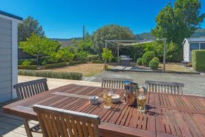 a wooden table with chairs and drinks on a patio at Corokia Villa - Peaceful, Modern Villa in Richmond in Richmond