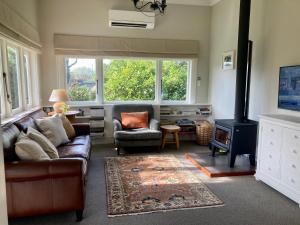 a living room with a couch and a stove at Country Bliss Cottage in Greytown