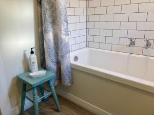 a bathroom with a bath tub and a table next to a stool at Country Bliss Cottage in Greytown +18 photos