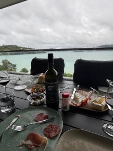 a table with a bottle of wine and plates of food at Frangipani 206 beachfront apartment in Hamilton Island +4 photos