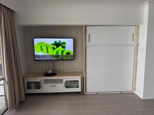 a living room with a refrigerator and a tv at Frangipani 206 beachfront apartment in Hamilton Island