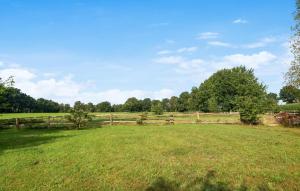 a field with a fence and trees in the background at Beautiful Apartment In Wingst in Wingst +9 photos