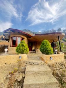 a house on a hill with a man standing in front of it at The Cob House in Chauntrā